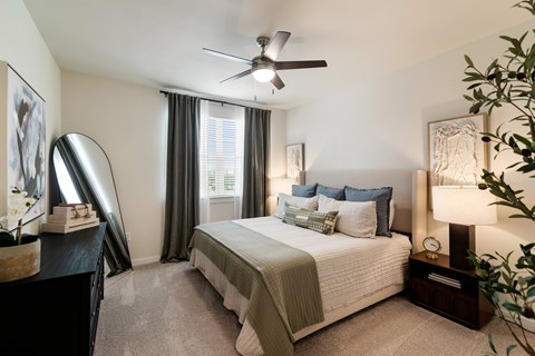 A bedroom with a large bed and a ceiling fan.