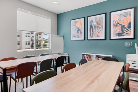 a communal table and chairs in a classroom with pictures on the wall