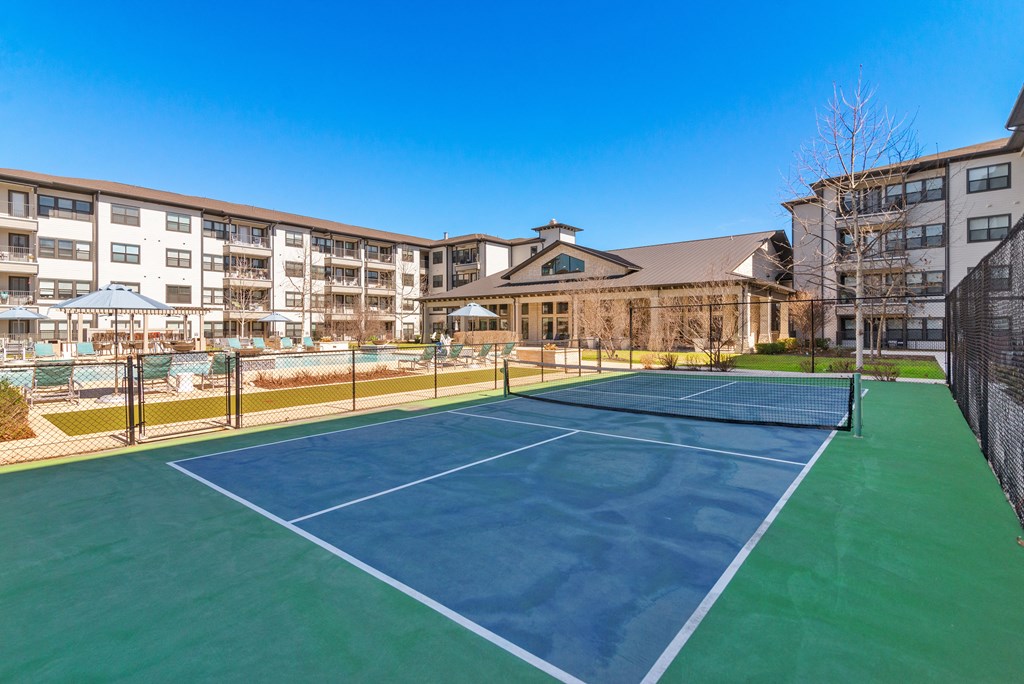 furnished tennis court with apartments in the background