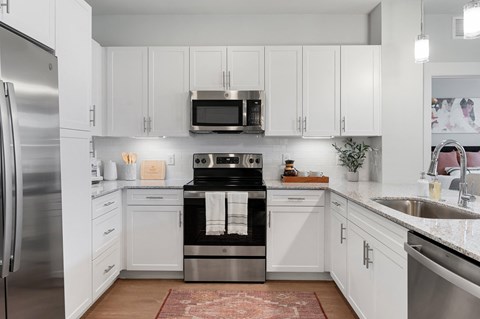 a white kitchen with stainless steel appliances and white cabinets