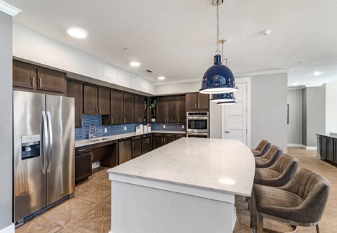 a communal clubhouse kitchen with a large island and chairs at a senior apartment community