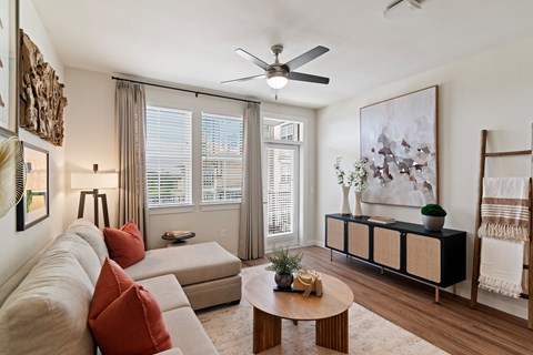 A living room with a beige couch, a wooden coffee table, and a large painting on the wall.