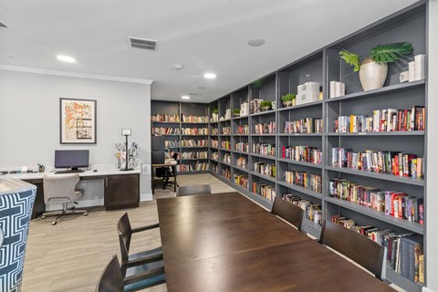 a library with a long table with chairs at a senior apartment community