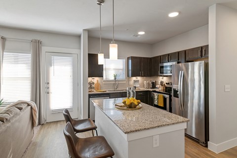a kitchen with stainless steel appliances, granite counter tops, and countertop seating at a senior apartment community