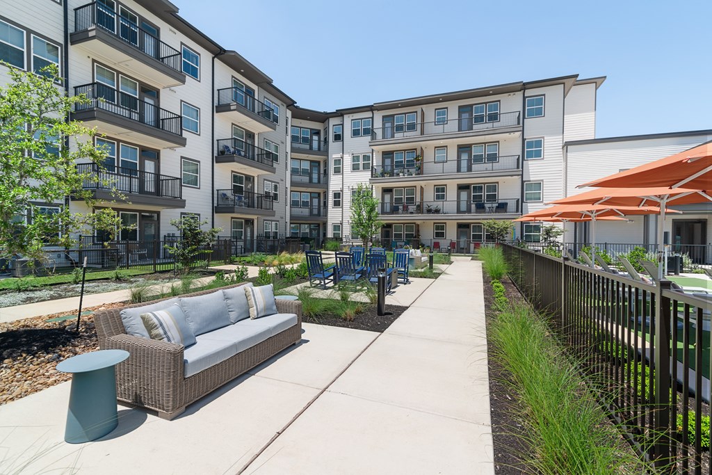 a patio with a couch and tables in front of an apartment building