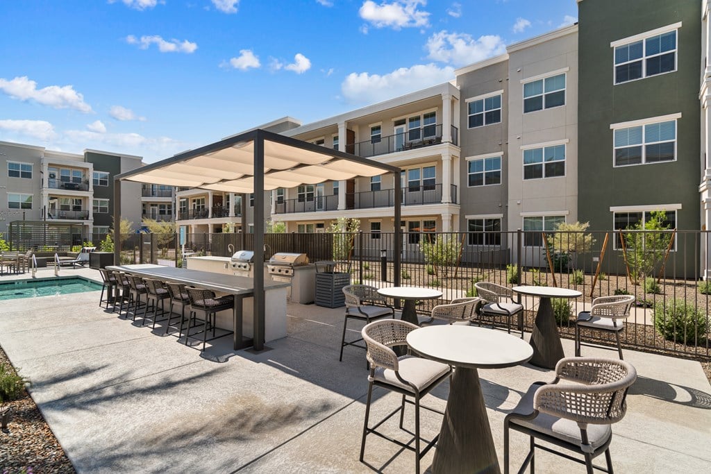 A patio with a table and chairs is surrounded by apartment buildings.