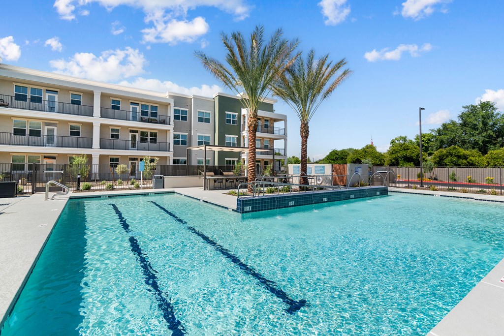 A swimming pool in front of a multi-story apartment building.