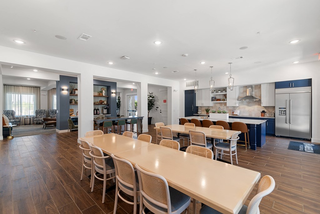 a communal dining room with tables and chairs and a kitchen