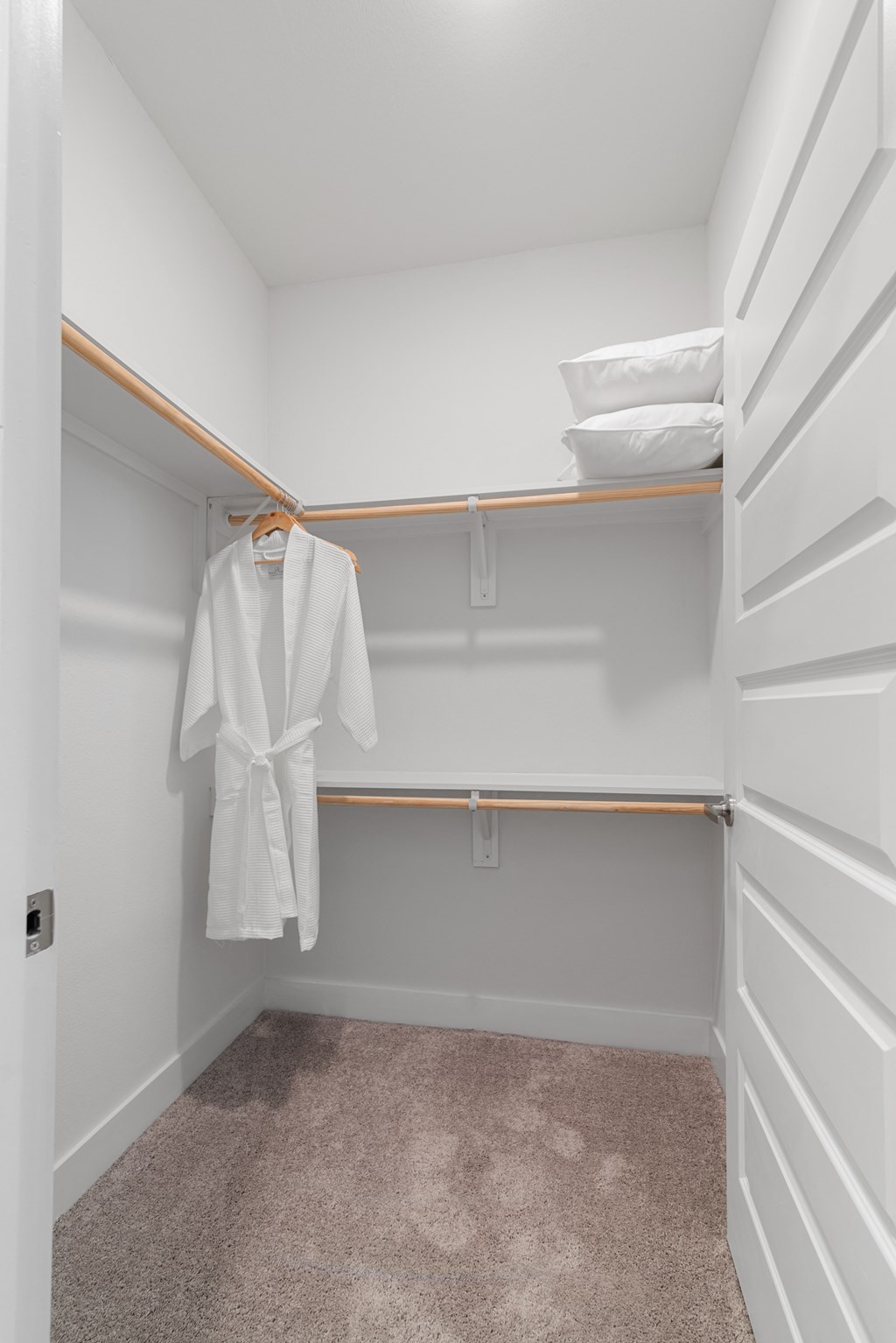 a walk in closet with a white robe hanging on the wall