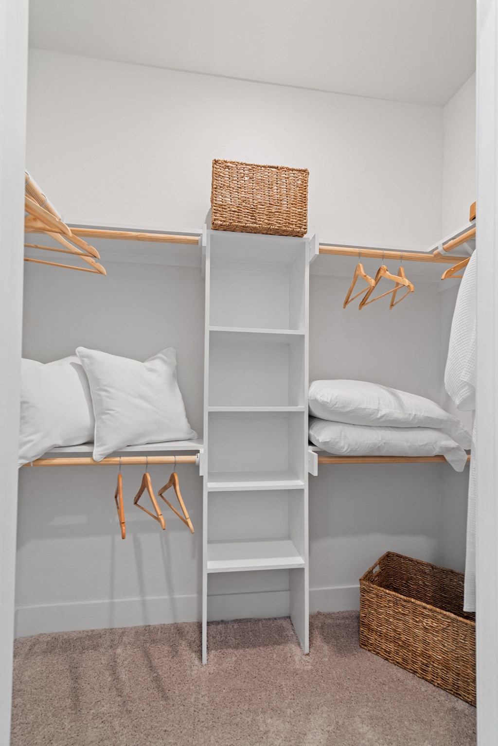a white closet with white shelves and white pillows and a basket