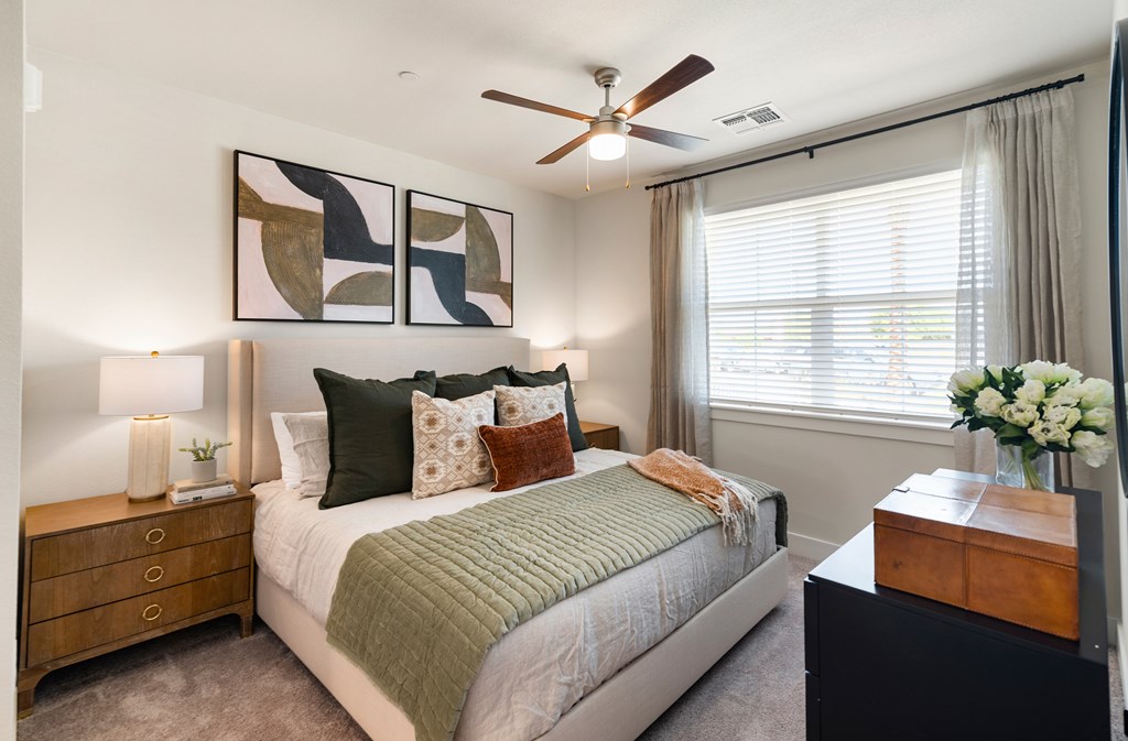 A bedroom with a bed, nightstand, and a ceiling fan.