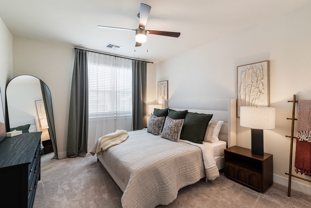 A bedroom with a bed, nightstand, and a ceiling fan.