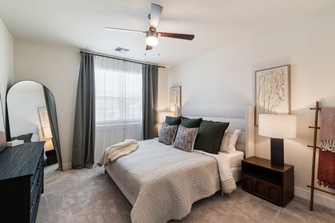 A bedroom with a bed, nightstand, and a ceiling fan.
