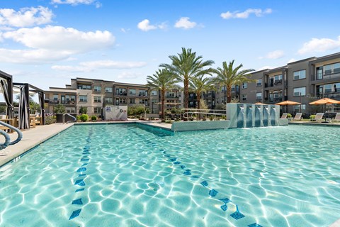 A swimming pool with blue lane markers in front of apartment buildings.