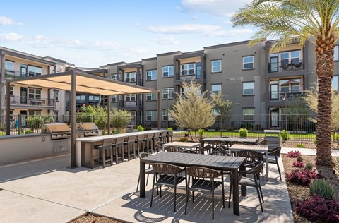 A patio with tables and chairs is surrounded by apartment buildings.