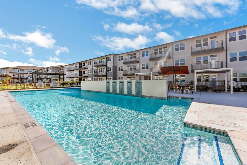 a swimming pool with an apartment building in the background