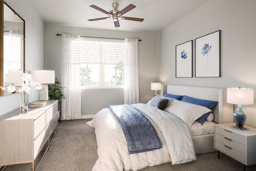 a bedroom with a queen-sized bed and ceiling fan and windows at a senior apartment community