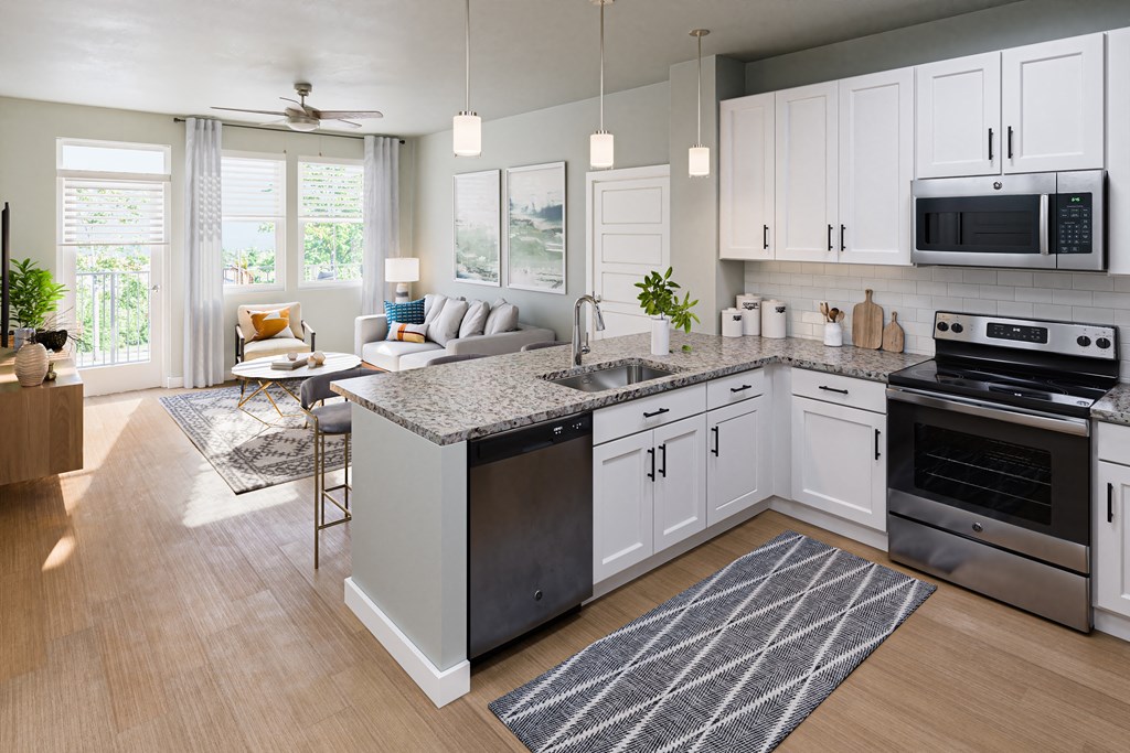 an open concept kitchen and living room with stainless steel appliances and white cabinets at a senior apartment community
