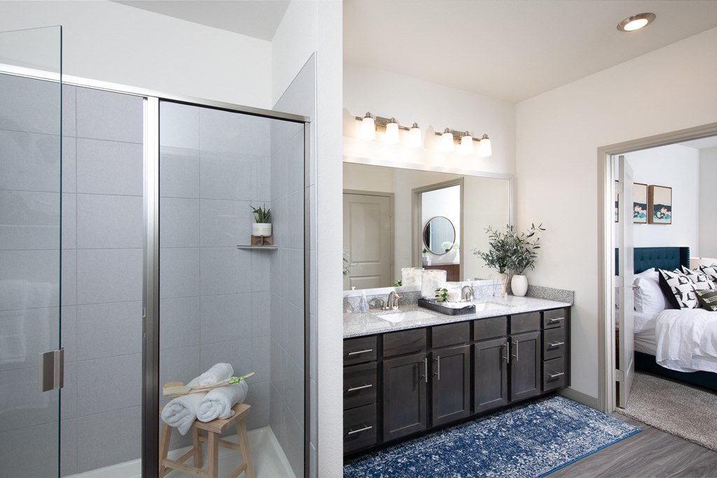 a bathroom with a glass walk-in shower and double sink at a senior apartment community
