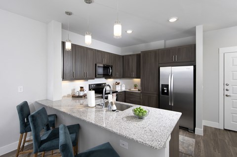 a kitchen with a marble counter top and a stainless steel refrigerator