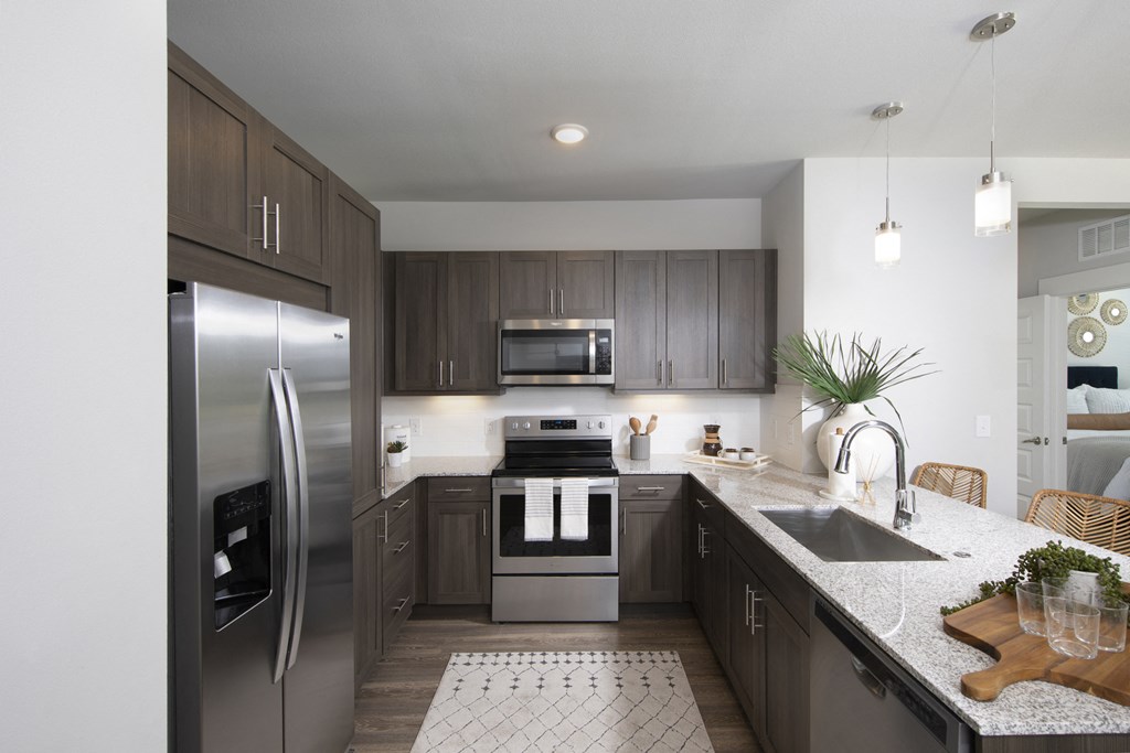 a kitchen with stainless steel appliances and granite countertops at a senior apartment community