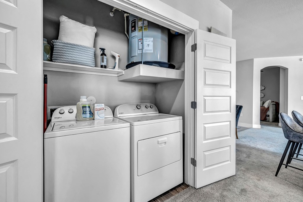 a small laundry room with a washer and dryer and a closet with shelves