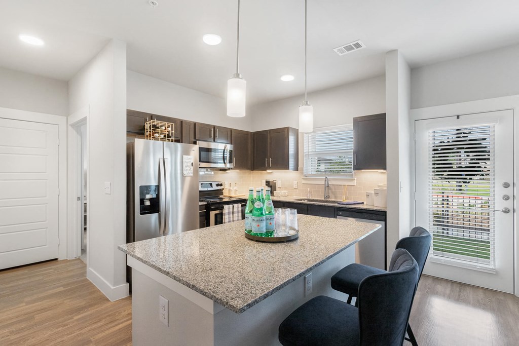 a kitchen with stainless steel appliances, granite countertops, and countertop seating at a senior apartment community
