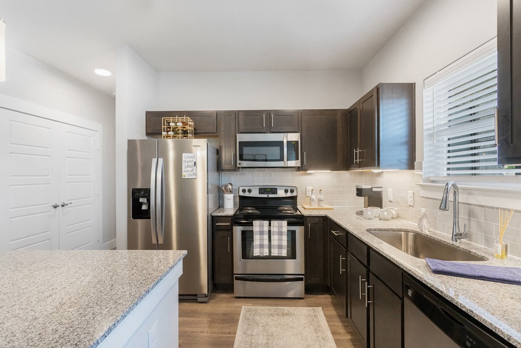 a kitchen with stainless steel appliances and granite countertops at a senior apartment community