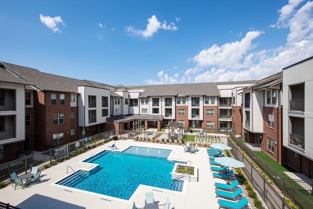 an aerial view of a resort-style swimming pool and courtyard at a senior apartment community