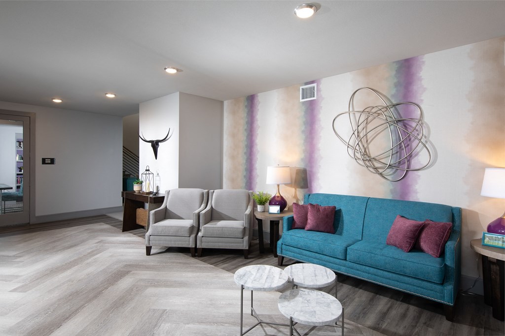 a living room with a blue couch and two white chairs
