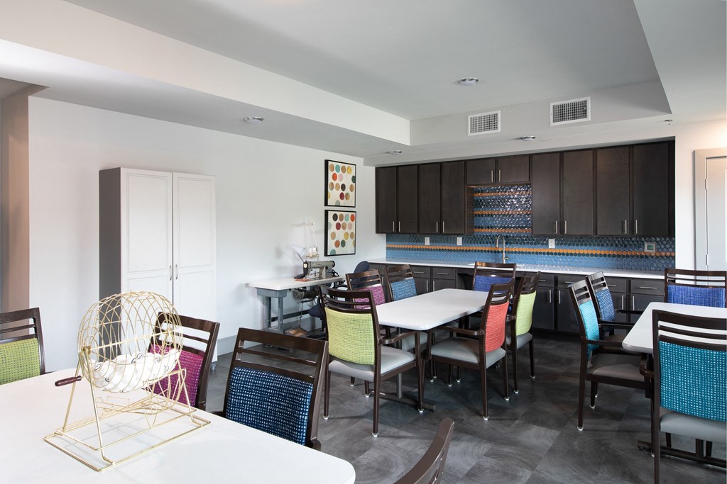 a communal dining room with tables and chairs and a kitchen