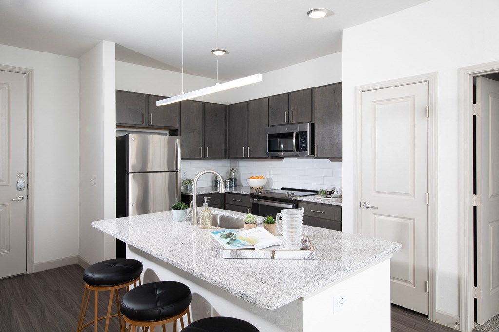 a kitchen with a marble counter top and a stainless steel refrigerator