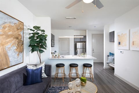 a living room with a couch and a kitchen with bar stools