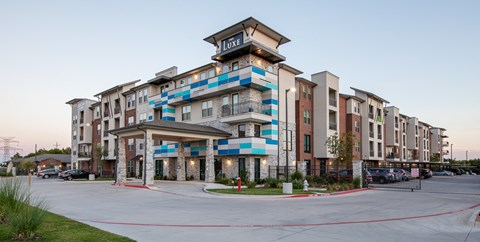 an apartment building with blue and white facade and a parking lot