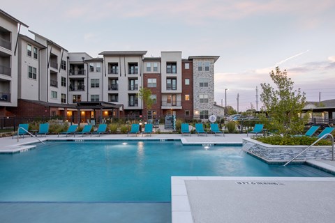a resort-style swimming pool and lounge chairs at a senior apartmetn community