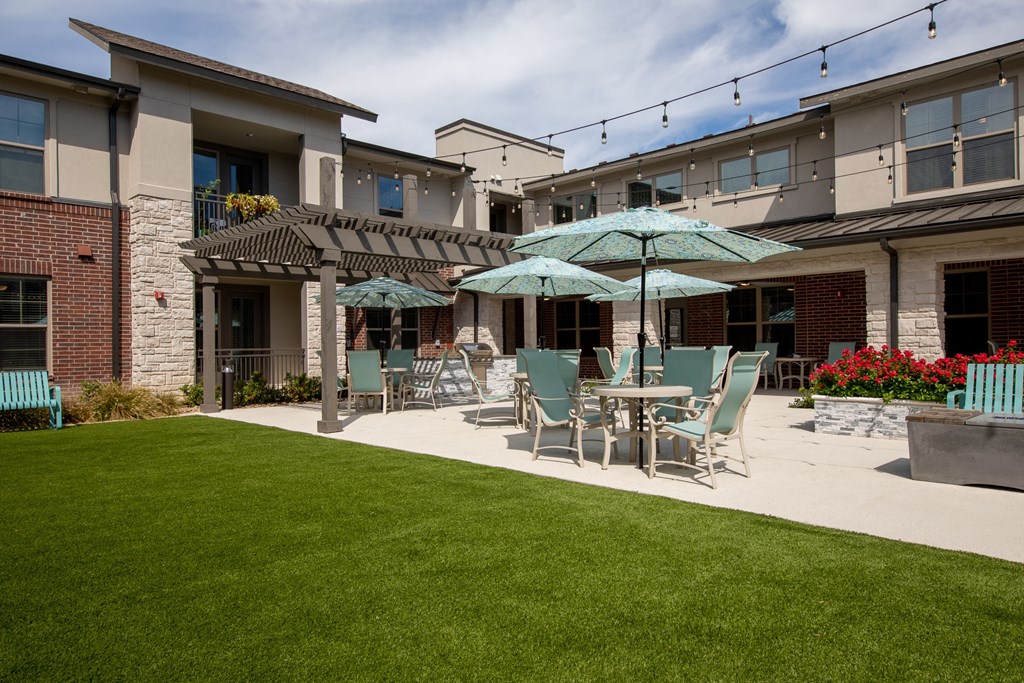 a patio with tables and chairs and umbrellas in front of a building