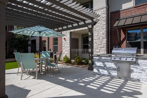 a patio with a table and chairs and a barbecue grill