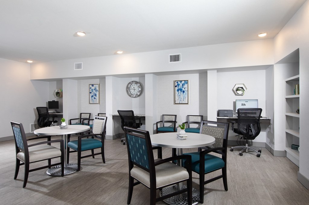 a common area with tables and chairs and a computer desk