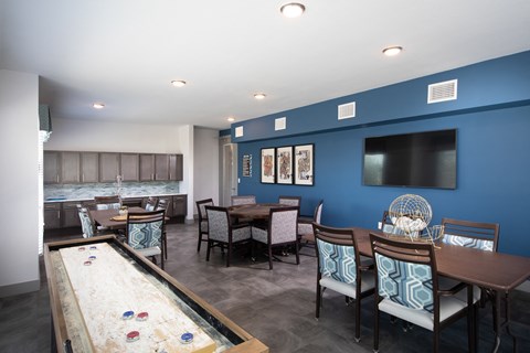 a game room with card tables and a table shuffleboard at a senior apartment community