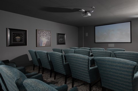 a media room with chairs and a screen at a senior apartment community