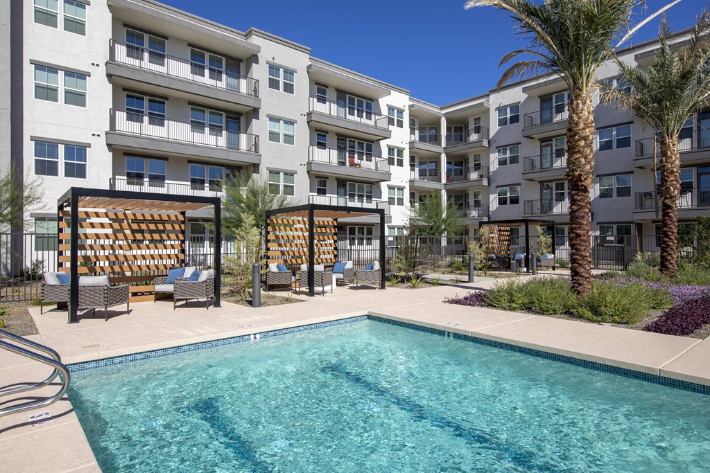 a swimming pool in front of an apartment building with palm trees