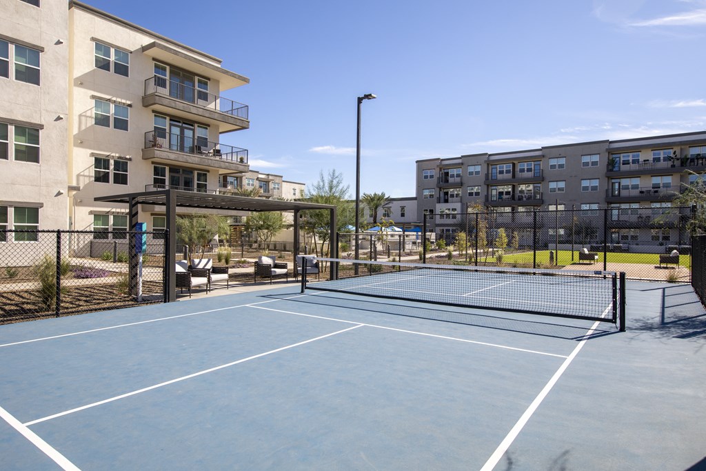 a blue tennis court with apartments in the background