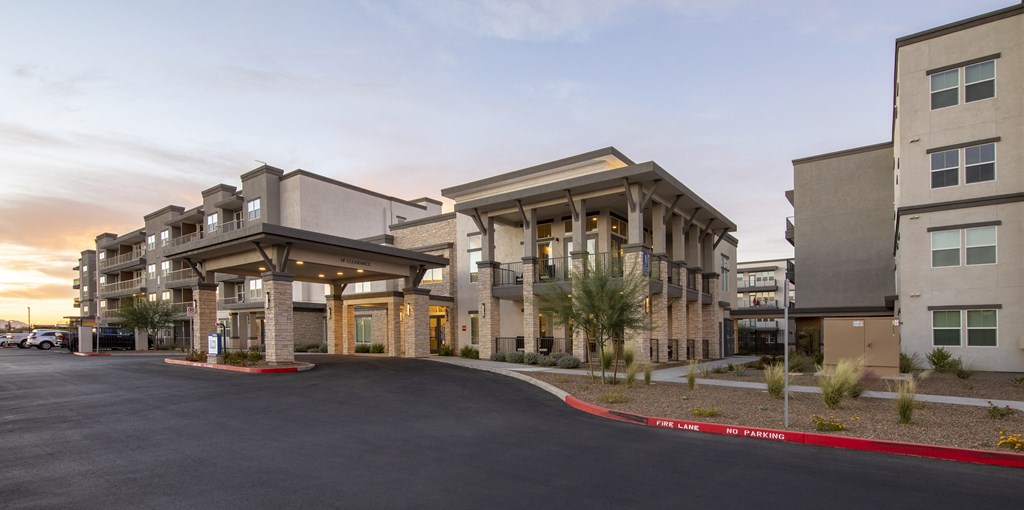 an exterior view of an apartment complex with a street and a sunset in the background