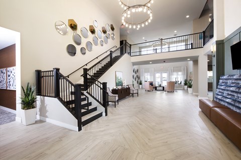 a large living room with a staircase and a lobby with couches and chairs