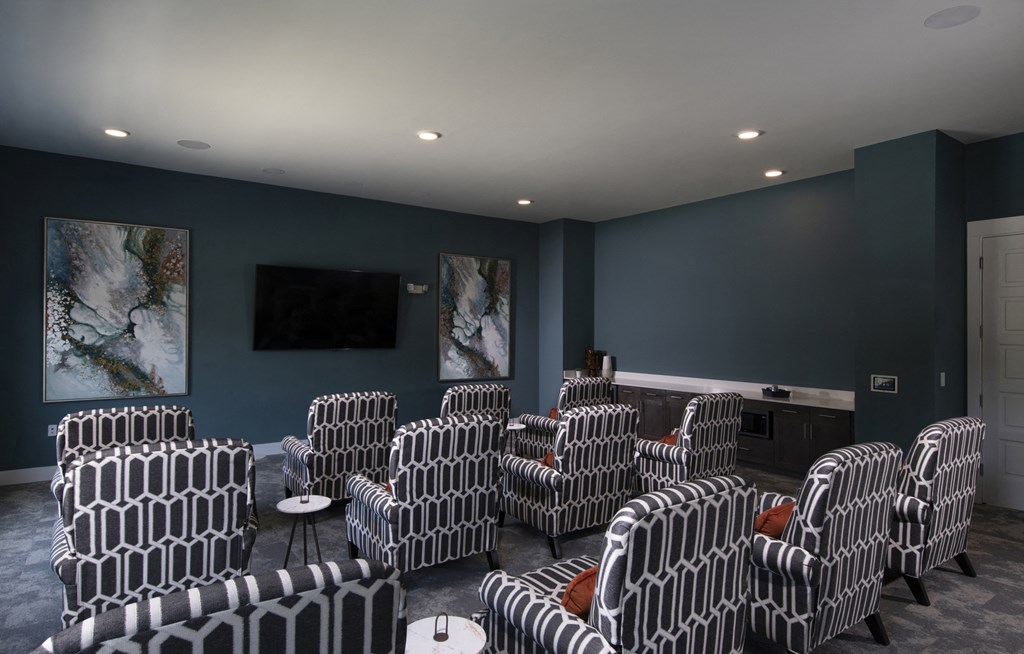 a media room with lounge chairs and a large television at a senior apartment community