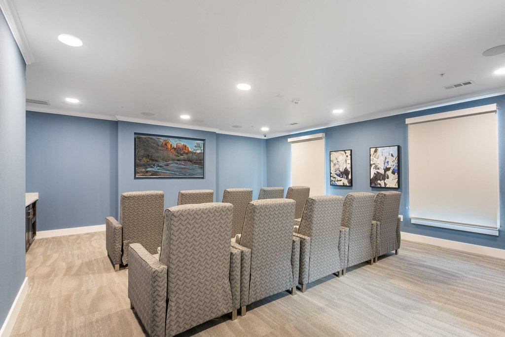 a media room with lounge chairs and a large television at a senior apartment community