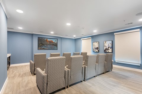 a media room with lounge chairs and a large television at a senior apartment community