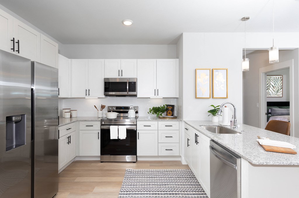 a kitchen with stainless steel appliances and granite countertops at a senior apartment community