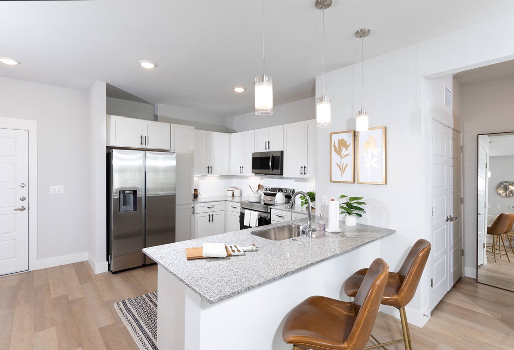 a kitchen with stainless steel appliances and granite countertops at a senior apartment community