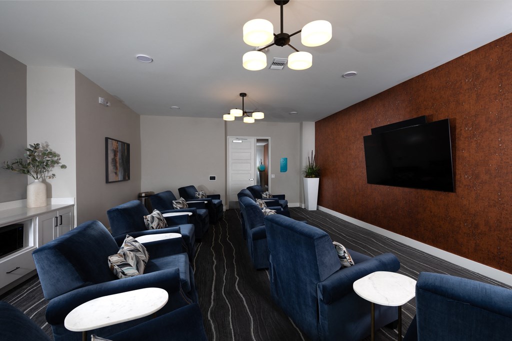 a media room with comfortable chairs and a screen at a senior apartment community